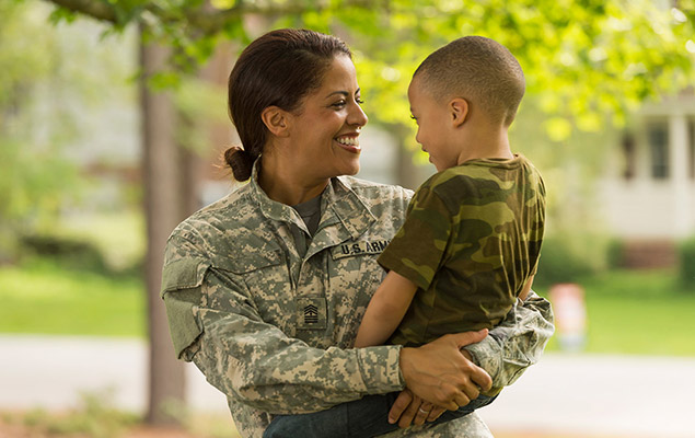 US Army personnel holding a child and smiling