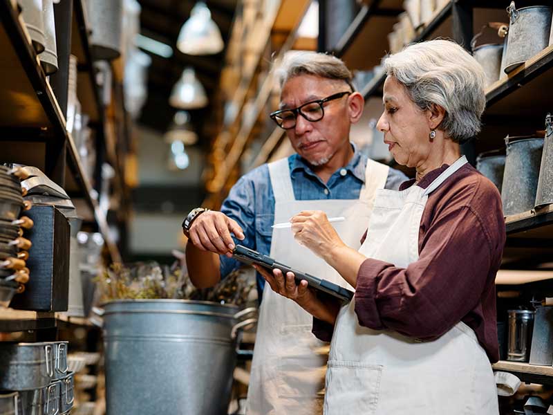 Older business owner couple in store working on inventory
